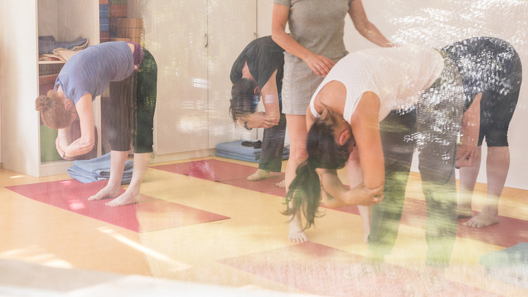 Yoga-Lehrerin leitet Gruppe zu Übungen an Yoga-Lehrerin leitet Gruppe zu Übungen an