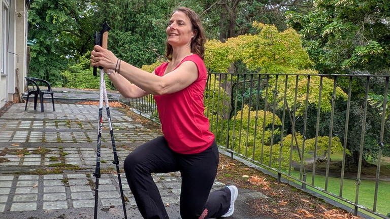 Therapeutin führt Übung mithilfe von Nordic Walking Stöcken aus Therapeutin führt Übung mithilfe von Nordic Walking Stöcken aus