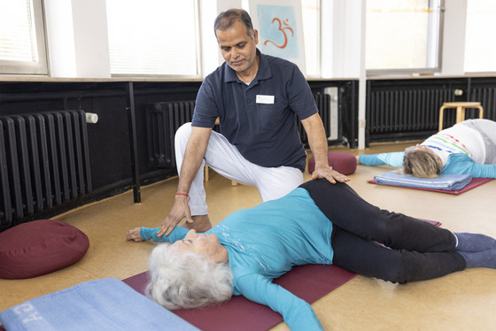 Yoga-Therapeut unterstützt Patientin bei Drehungs-Übung Yoga-Therapeut unterstützt Patientin bei Drehungs-Übung