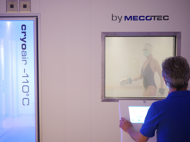 Patientin in Bewegung in der Kältekammer unter Aufsicht einer Fachkraft