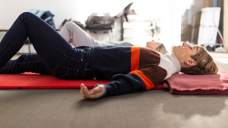 Frauen liegen mit geschlossenen Augen auf Matte und praktizieren achtsames Yoga Frauen liegen mit geschlossenen Augen auf Matte und praktizieren achtsames Yoga