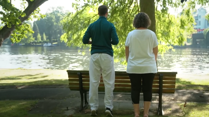Patientin führt Übungen mit Physiotherapeut in Park aus